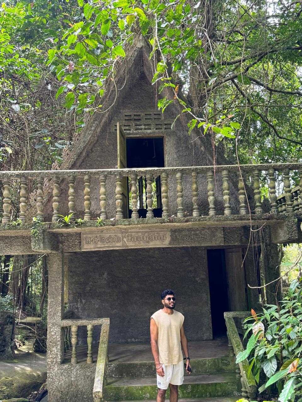 Traveller standing at a moss-covered jungle shrine in Southeast Asia