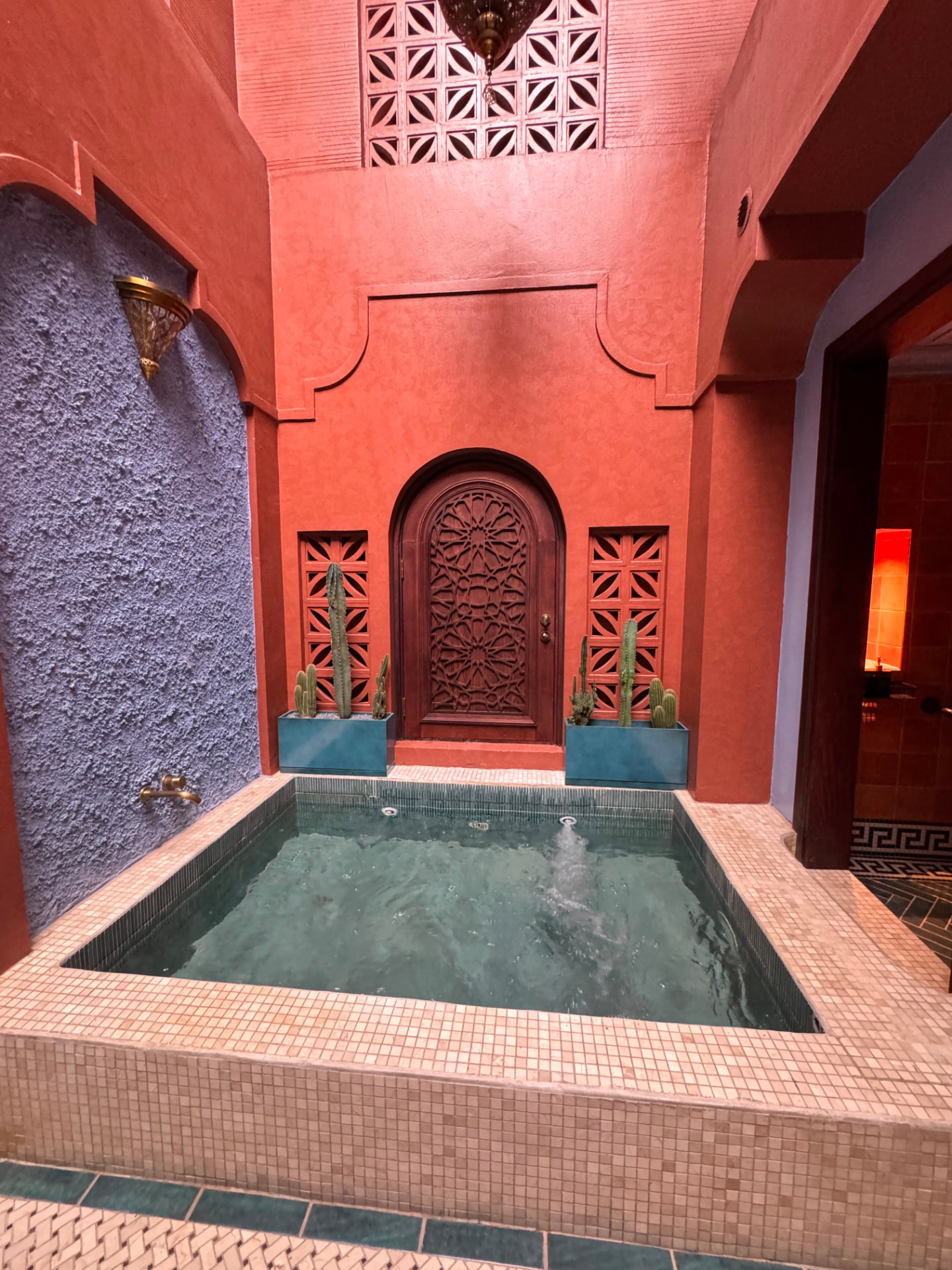 Terracotta courtyard with a tiled plunge pool and carved wooden door